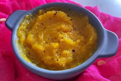 Pumpkin Puree topped with ground black pepper in a blue bowl on a pink napkin