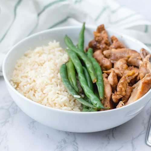 Roasted chicken strips with green bean and rice on white bowl