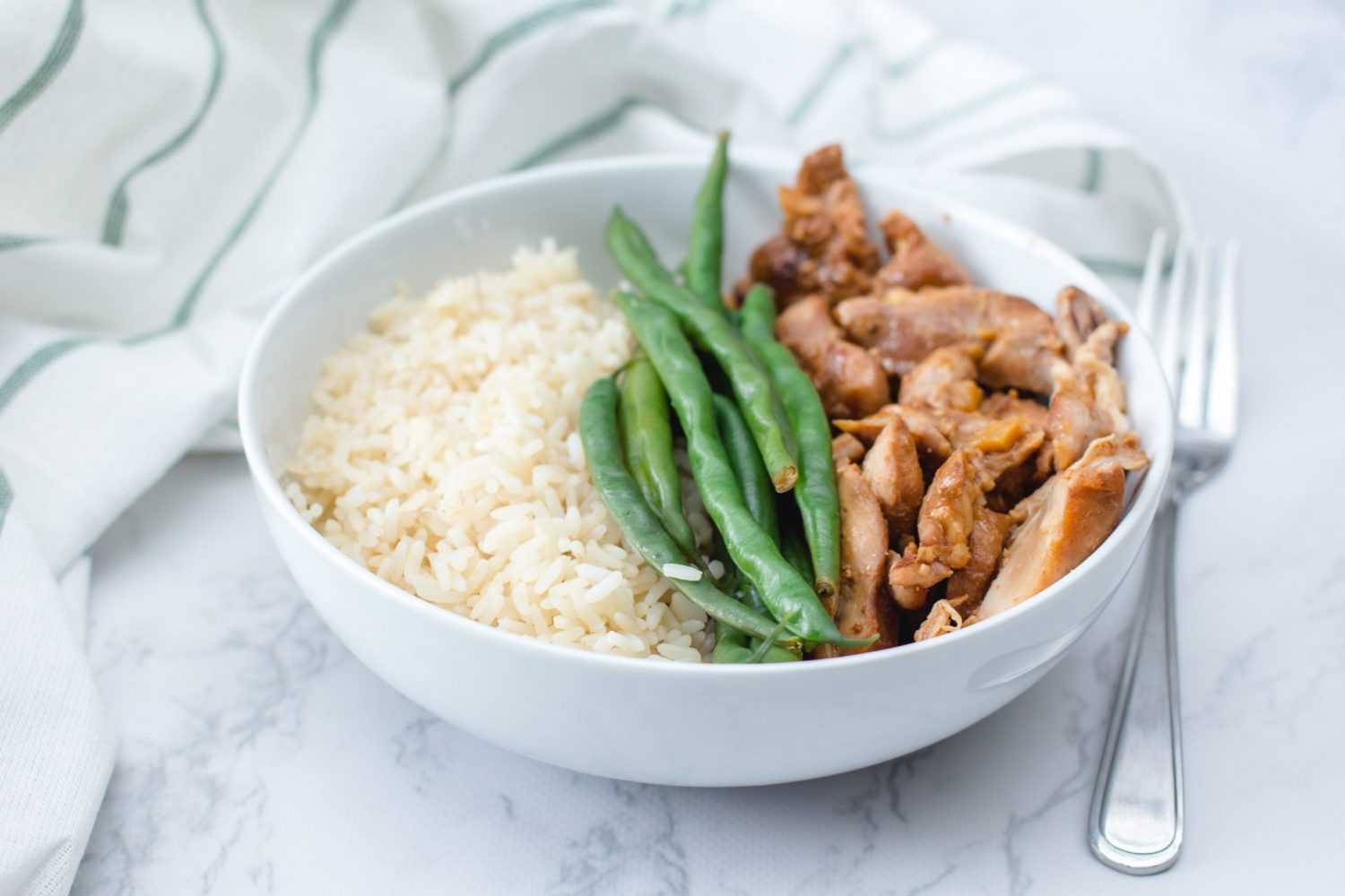 Roasted chicken strips with green bean and rice on white bowl