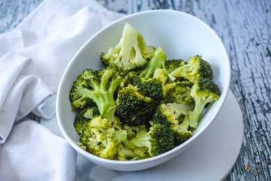 Steamed broccoli florets in white bowl top view