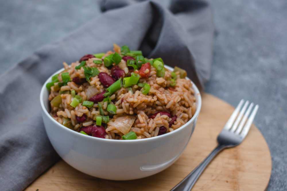 Rice mixed with red beans and onion topped with scallion with a fork on side