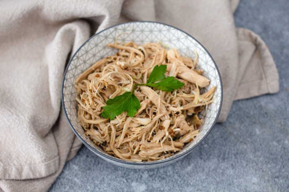 Shredded chicken in a bowl topped with parsley