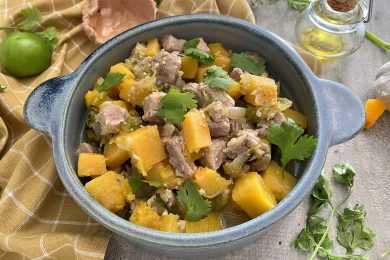 Pork loin cubes with butternut squash, parsley in green tomato and garlic sauce in blue bowl