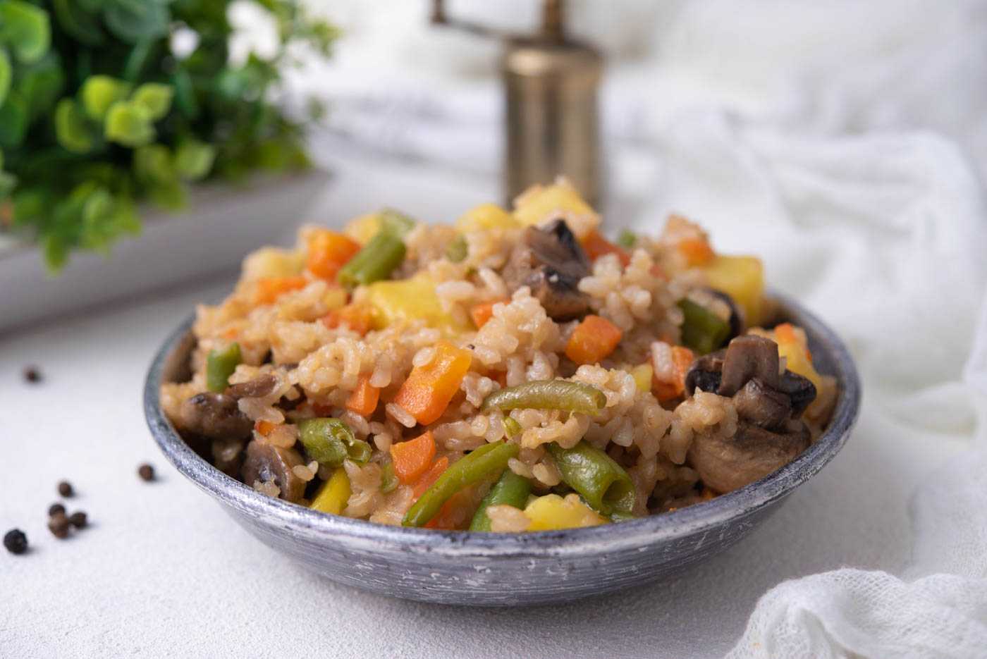 brown rice with corn, carrots pieces, green peas and mushroom in a blue bowl