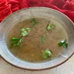 Clear turkey stock in a bowl with parsley on top
