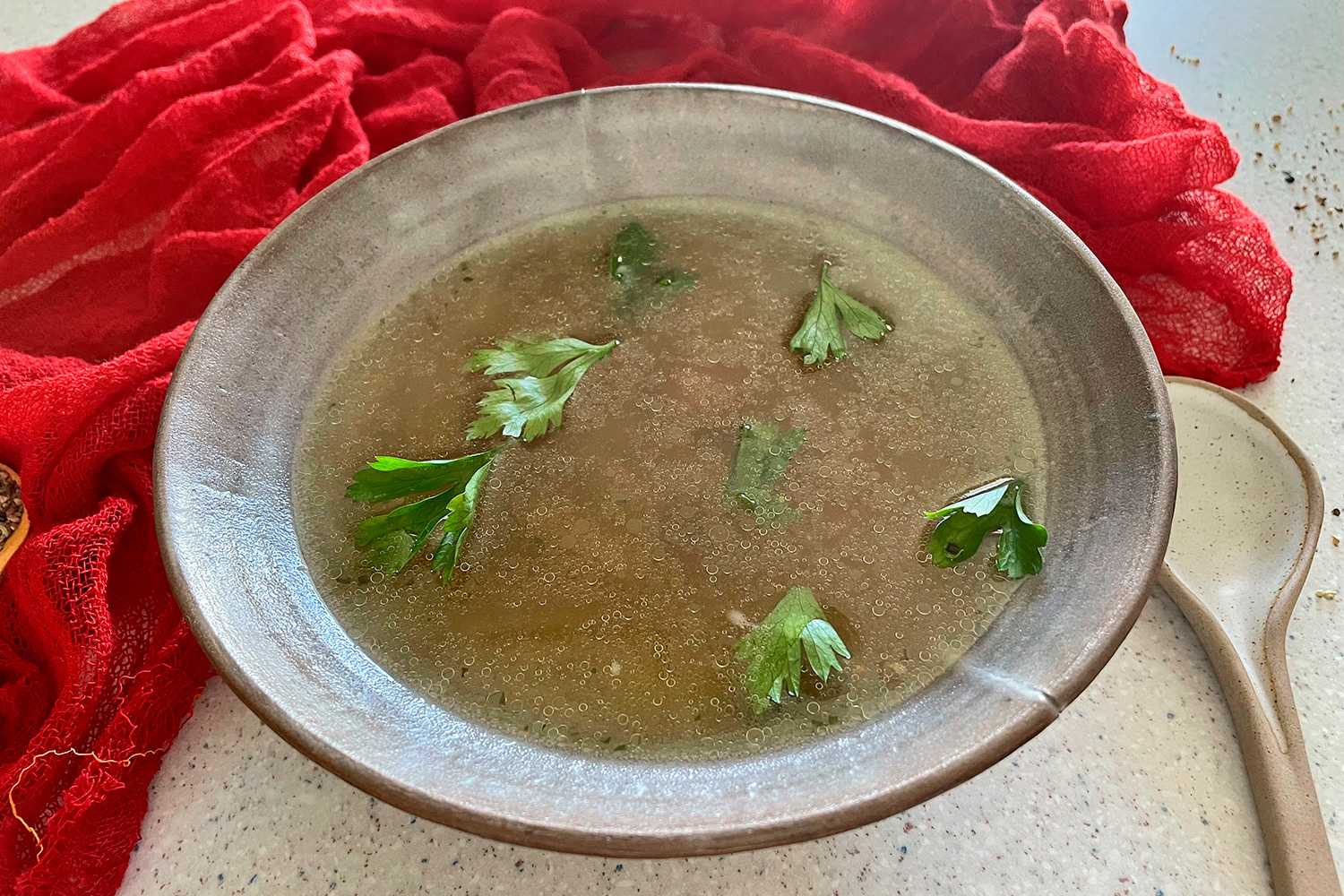 Clear turkey stock in a bowl with parsley on top
