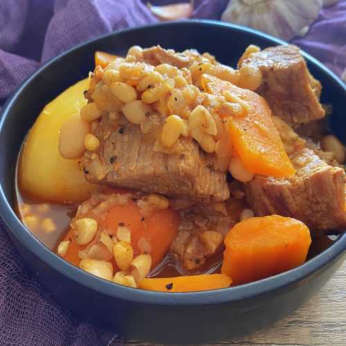 Beef chunks with chopped carrots, whole potato and white beans in red sauce