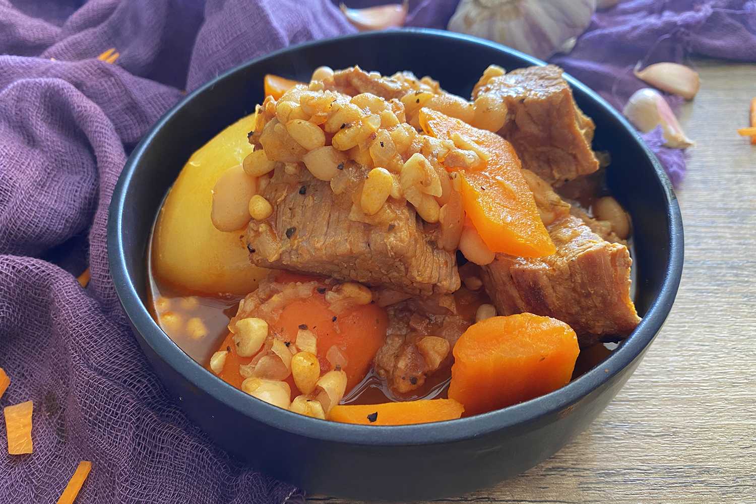 Beef chunks with chopped carrots, whole potato and white beans in red sauce