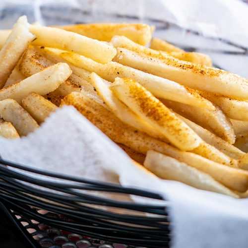 French fries with paprika, black pepper and salt inside a basket