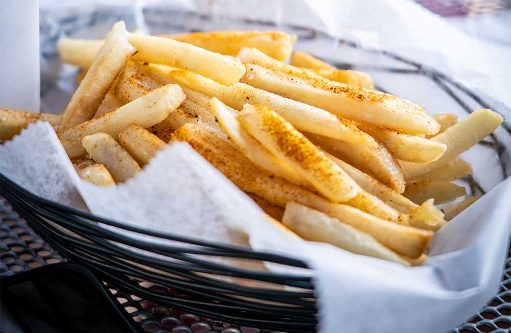French fries with paprika, black pepper and salt inside a basket