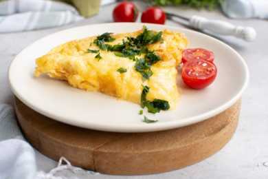 Egg bake slice with bacon, cheese and hash browns with cherry tomatoes on side topped with parsley