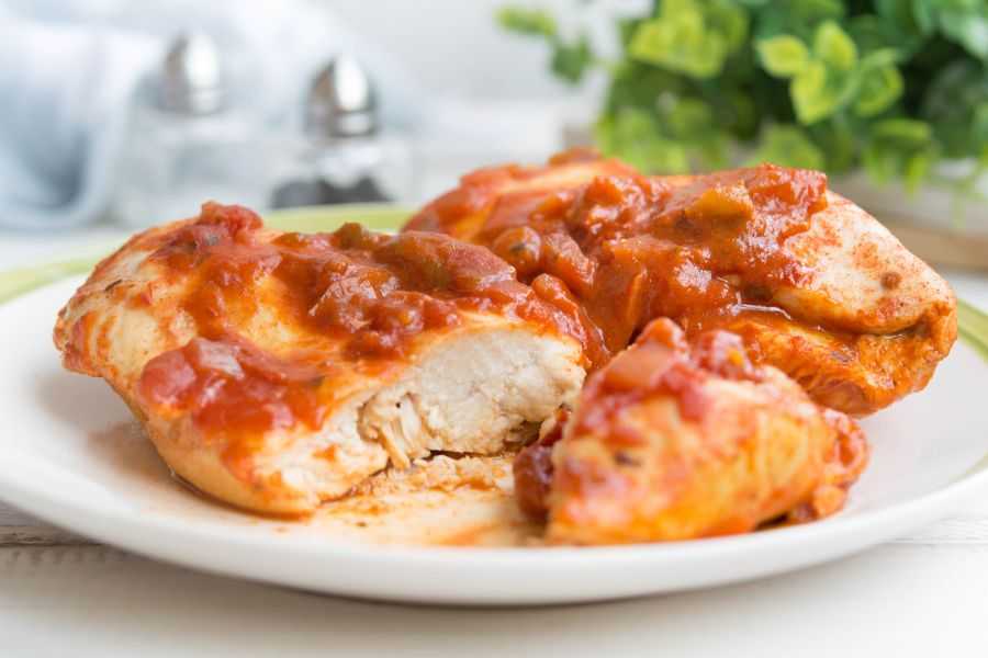 Chicken breasts topped with red salsa on plate