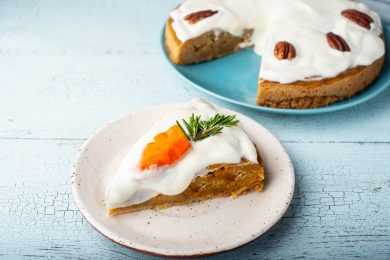 Carrot cake slice topped with cream cheese and a small carrot