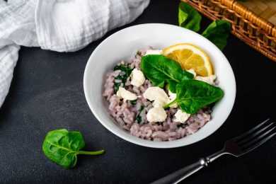 Arborio rice mixed with cheese and spinach with ricotta cubes, lemon slice and spinach leaves