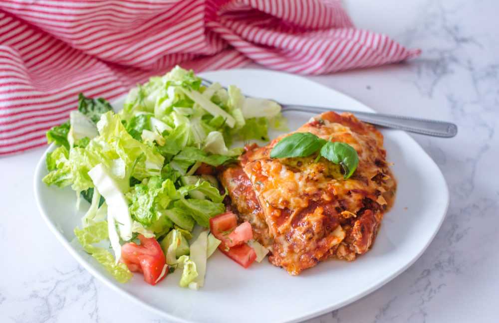 Lasagna with marinara sauce, mozzarella and parmesan cheese with lettuce and tomato salad on side