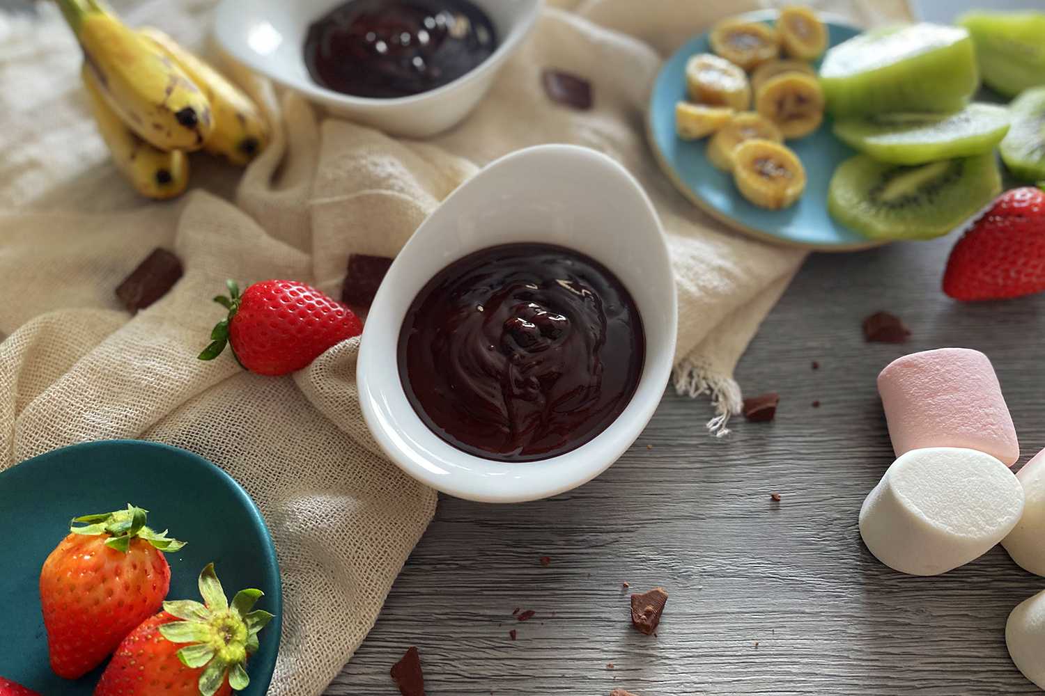 Chocolate fondue with marshmallows, strawberries and sliced kiwi and bananas