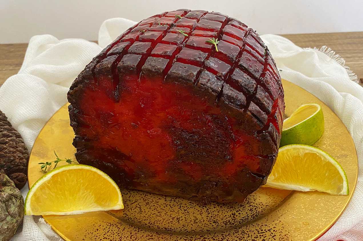 Homemade glazed ham with brown bbq frosting with a slice of lemon on side