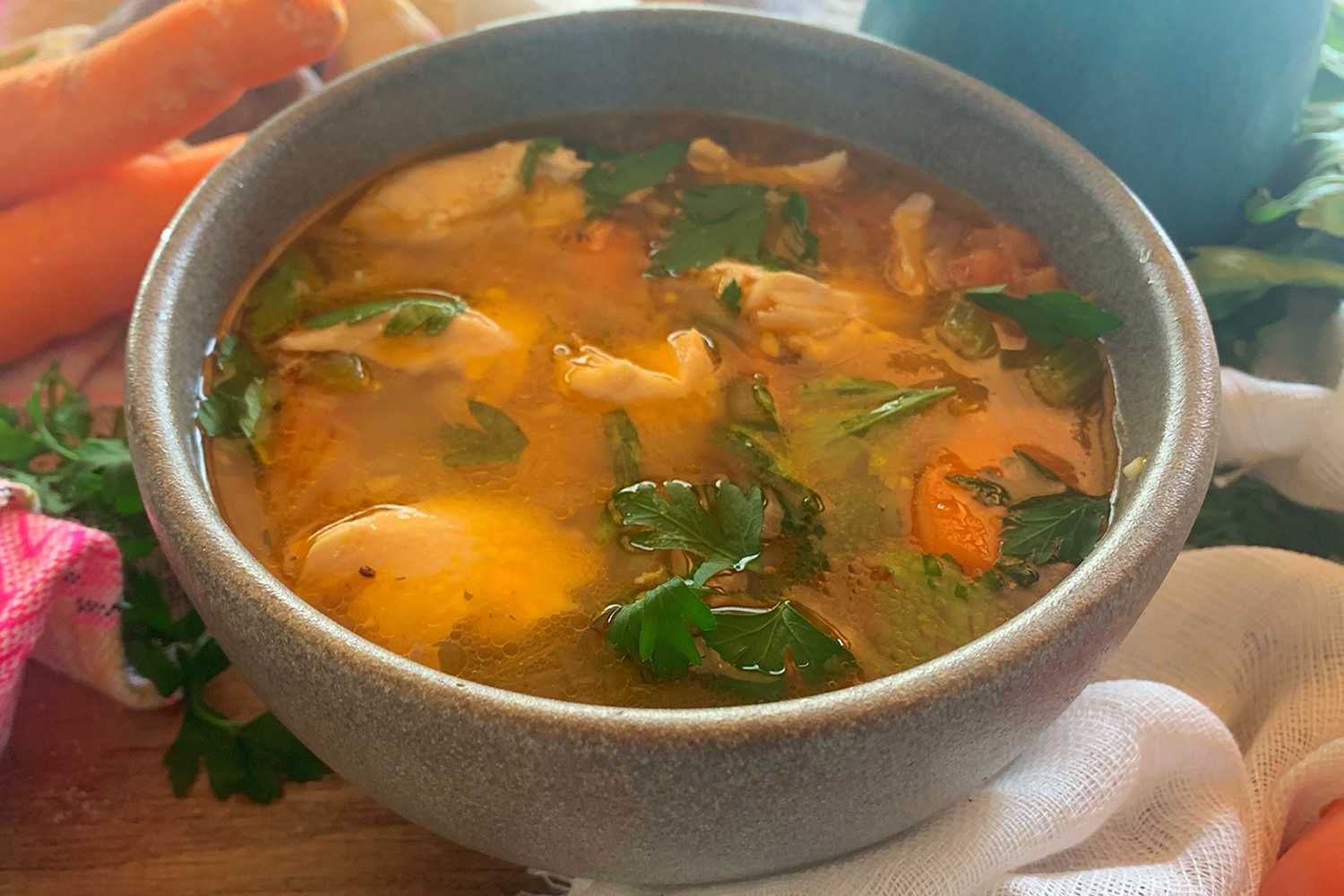 Fresh soup with salmon, carrot cubes and parsley in a grey bowl