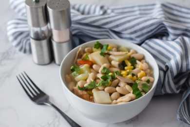 Chili with white kidney beans, chicken, potato cubes, corn and parsley on top