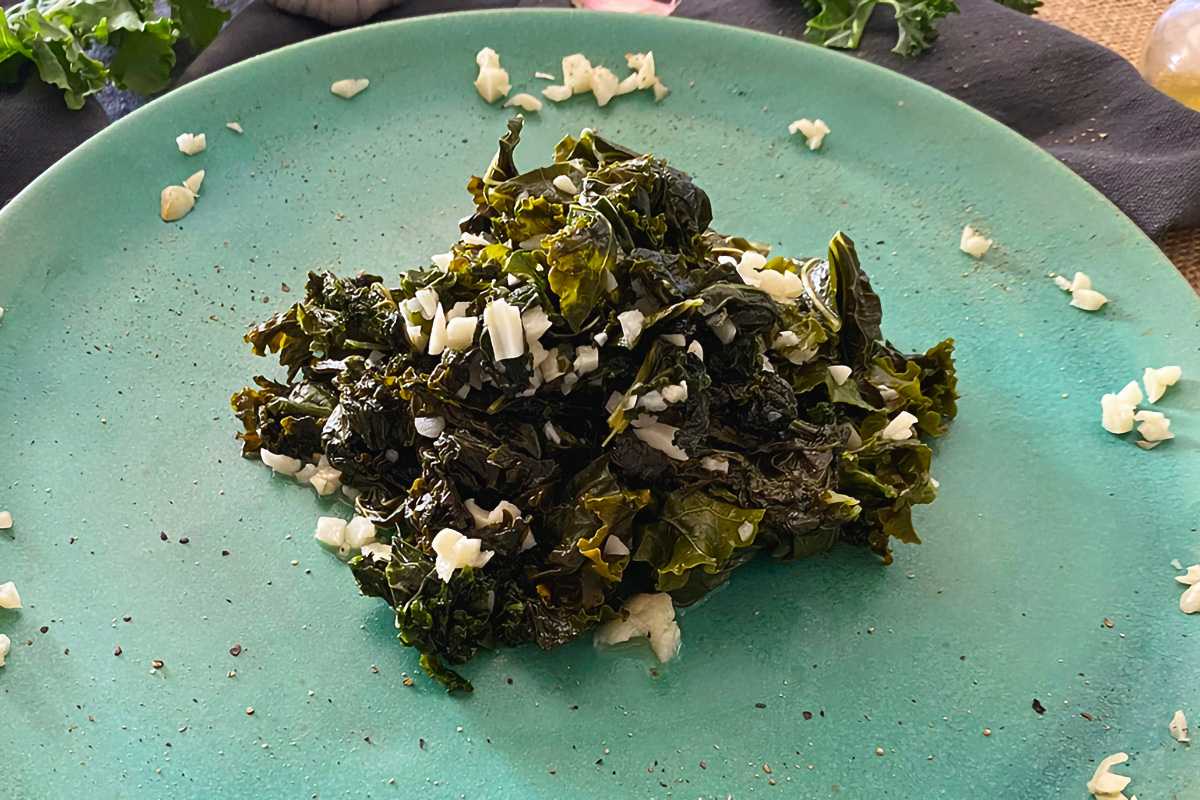 Cooked kale mixed with chopped garlic on a blue plate
