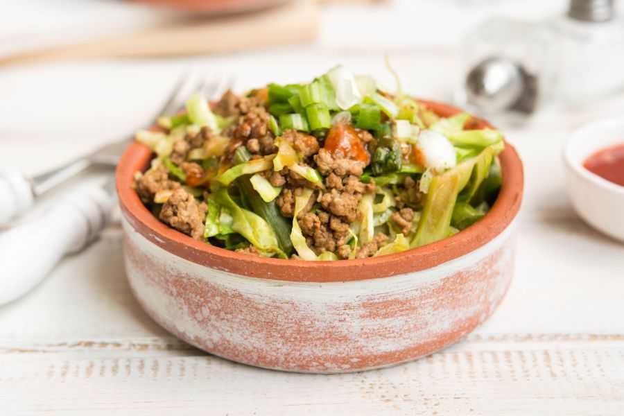 Ground beef with cabbage slices and chopped scallion in a brown bowl