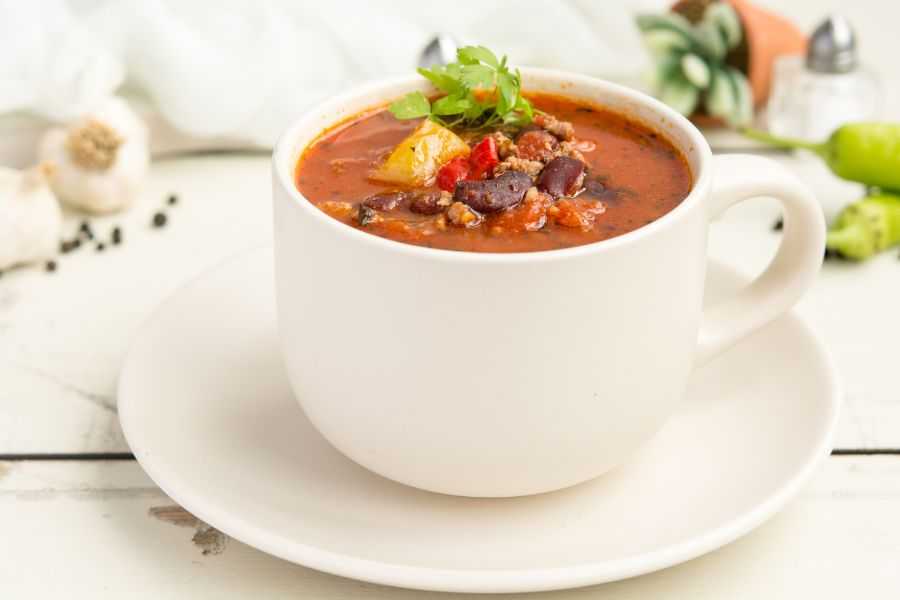 red soup with black beans, ground beef and veggies served in a white cup