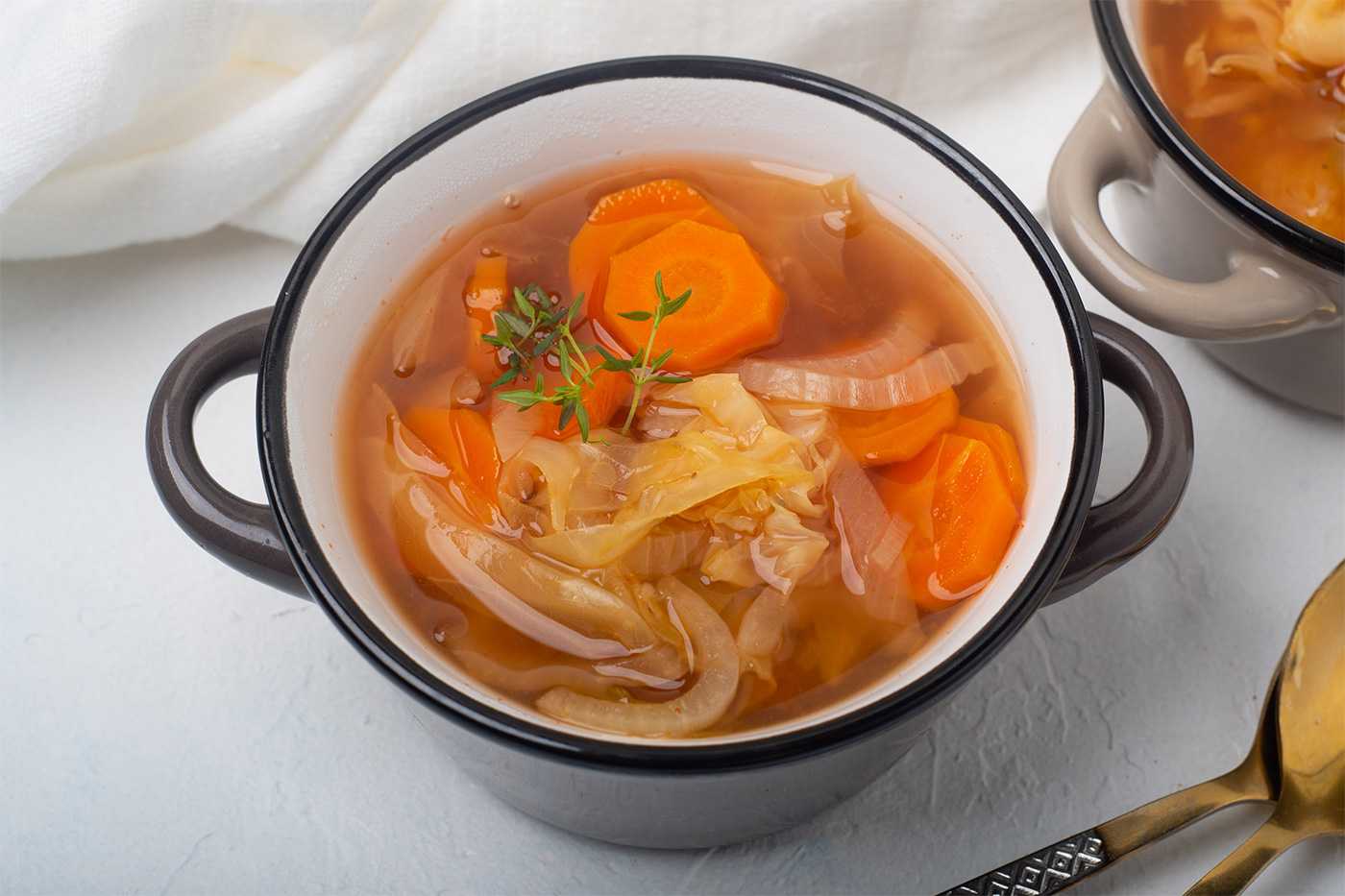 Clear soup fill with white cabbage, carrot slices, onion and spices