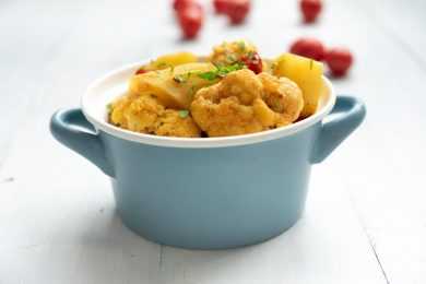 potato cubes with cauliflower florets in a small blue pot