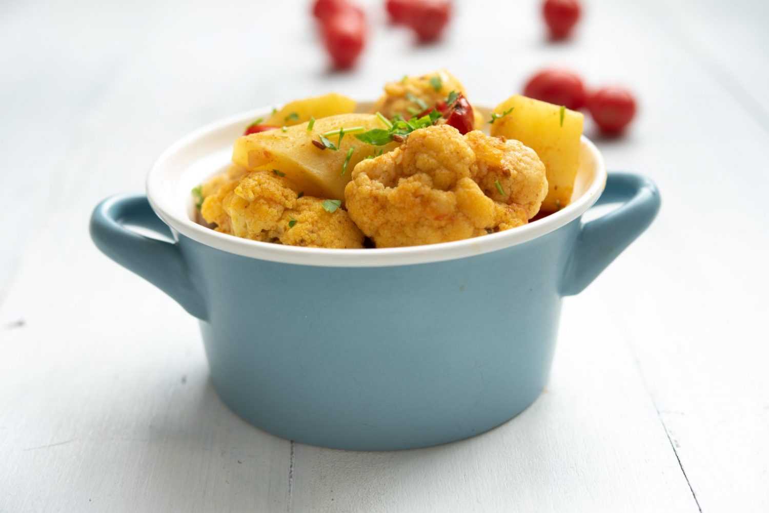 potato cubes with cauliflower florets in a small blue pot