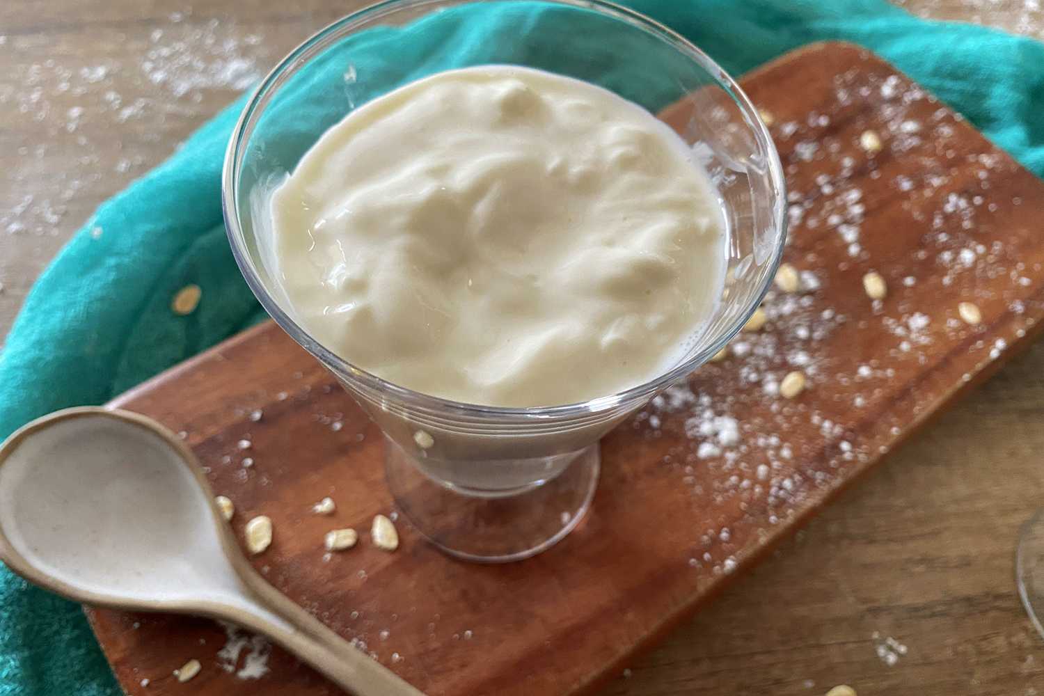 Greek yogurt in glass bowl on cutter board with spoon on side