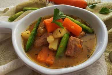 Beef stew with carrot, green beans, potatoes and beef cubes in brown sauce topped with parsley