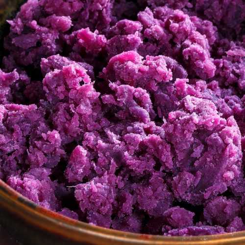 Mashed purple potatoes in brown bowl