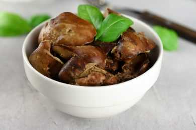 Roasted chicken livers with basil on top in white bowl