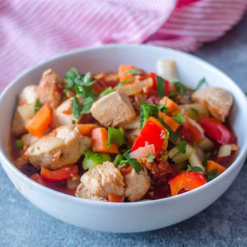 Chicken stew with bell peppers, carrots, celery and chicken cubes topped with parsley