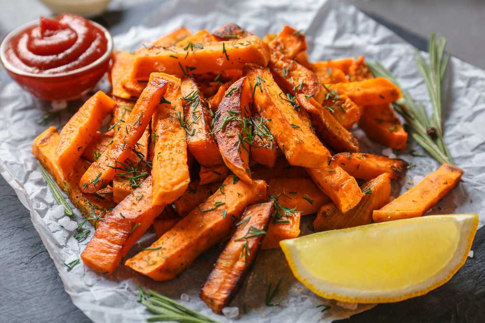 Sweet potato fries with slice of lemon and a small bowl of ketchup