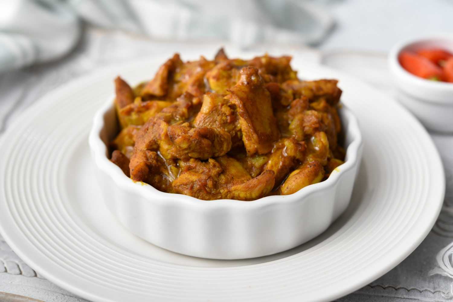 Chicken pieces in vindaloo sauce in white bowl