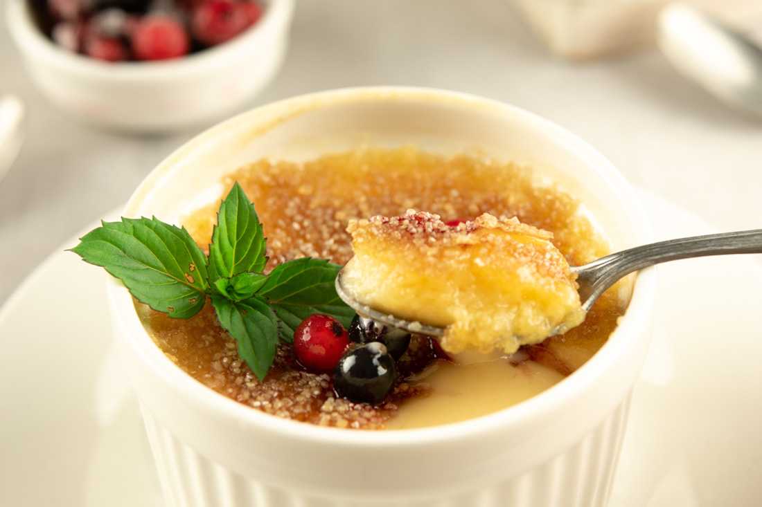Bowl of creme brulee, topped with cranberries and mint
