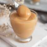 Dulce de Leche in a glass with a spoon with some of the spread