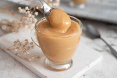 Dulce de Leche in a glass with a spoon with some of the spread