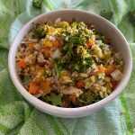 Brown rice mixed with corn, carrot, peas, broccoli and spices on white bowl