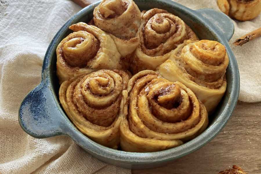 6 homemade cinnamon rolls in a blue bowl topped with cinnamon and sugar