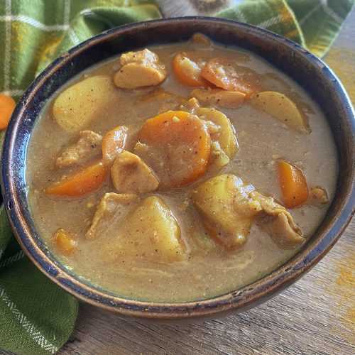 Chicken cubes, chopped carrot and potatoes in creamy curry sauce top view