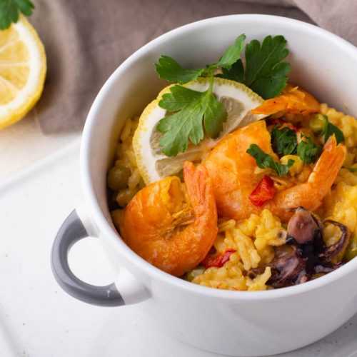 Yellow rice with shrimp, seafood mix, parsley and lemon slice on top