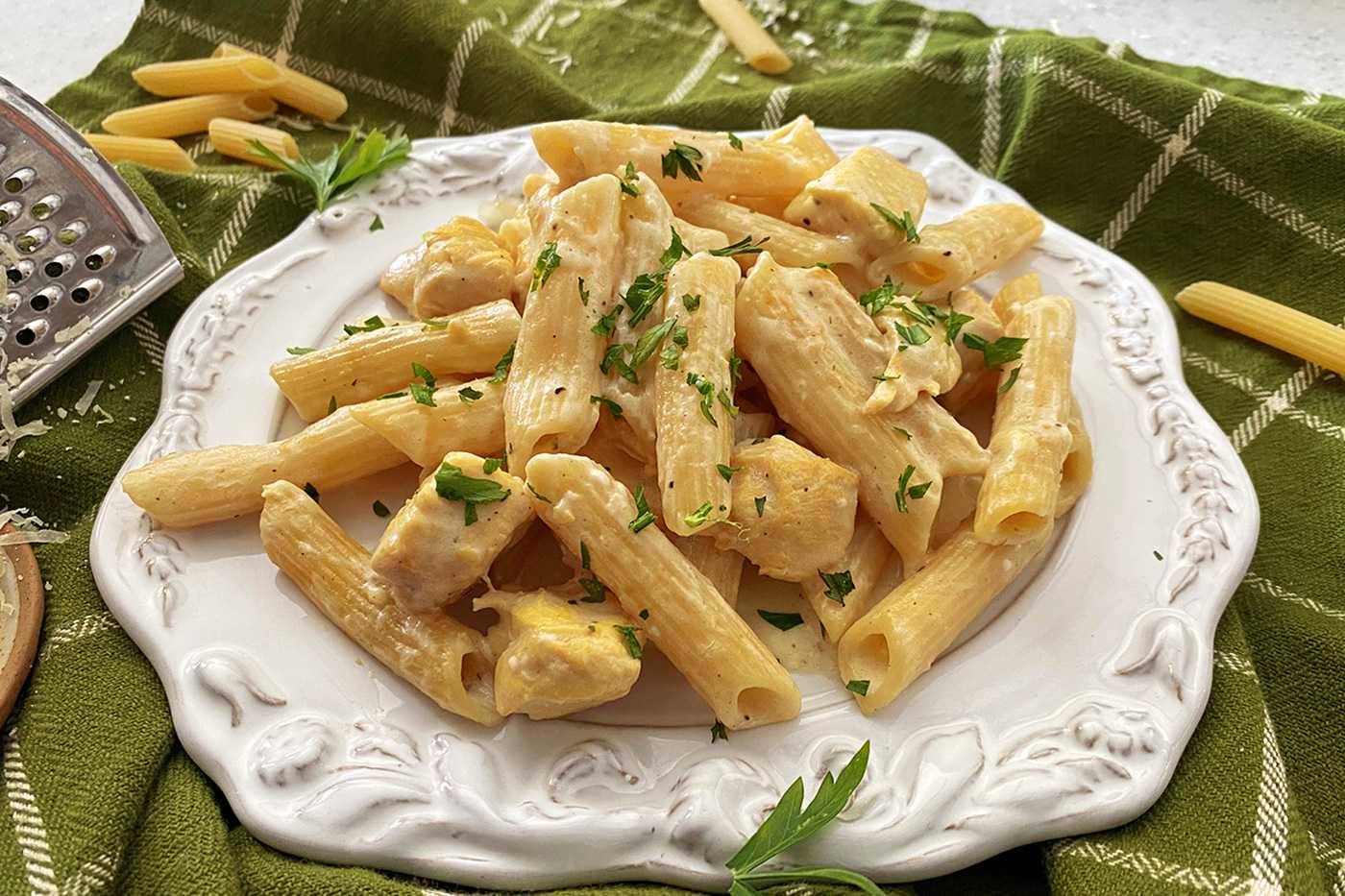 penne pasta with chicken chopped parsley cubes in a cheese sauce topped with