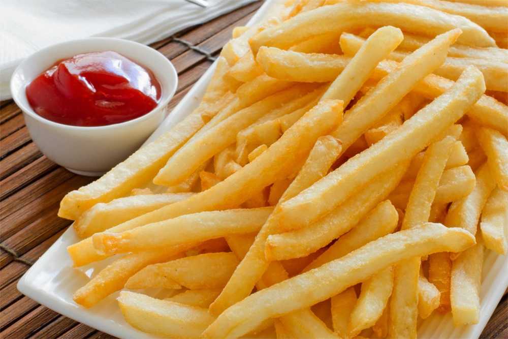 French fries on a square white plate with a small bowl of ketchup on side