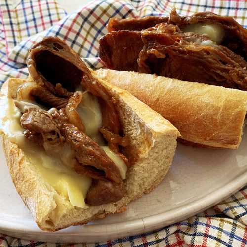 Sub rolls cut into half filled with chuck roast slices and melted cheese top view