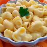Macaroni mixed with melted cheese with parsley on top in white bowl