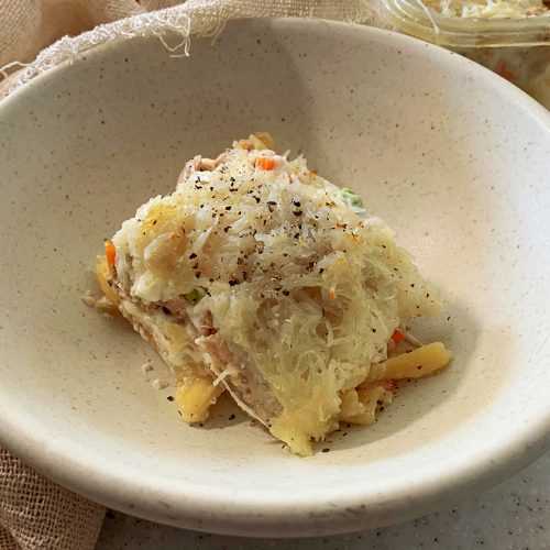 Penne pasta covered with tuna and vegetable mixture topped with shredded potatoes in white bowl