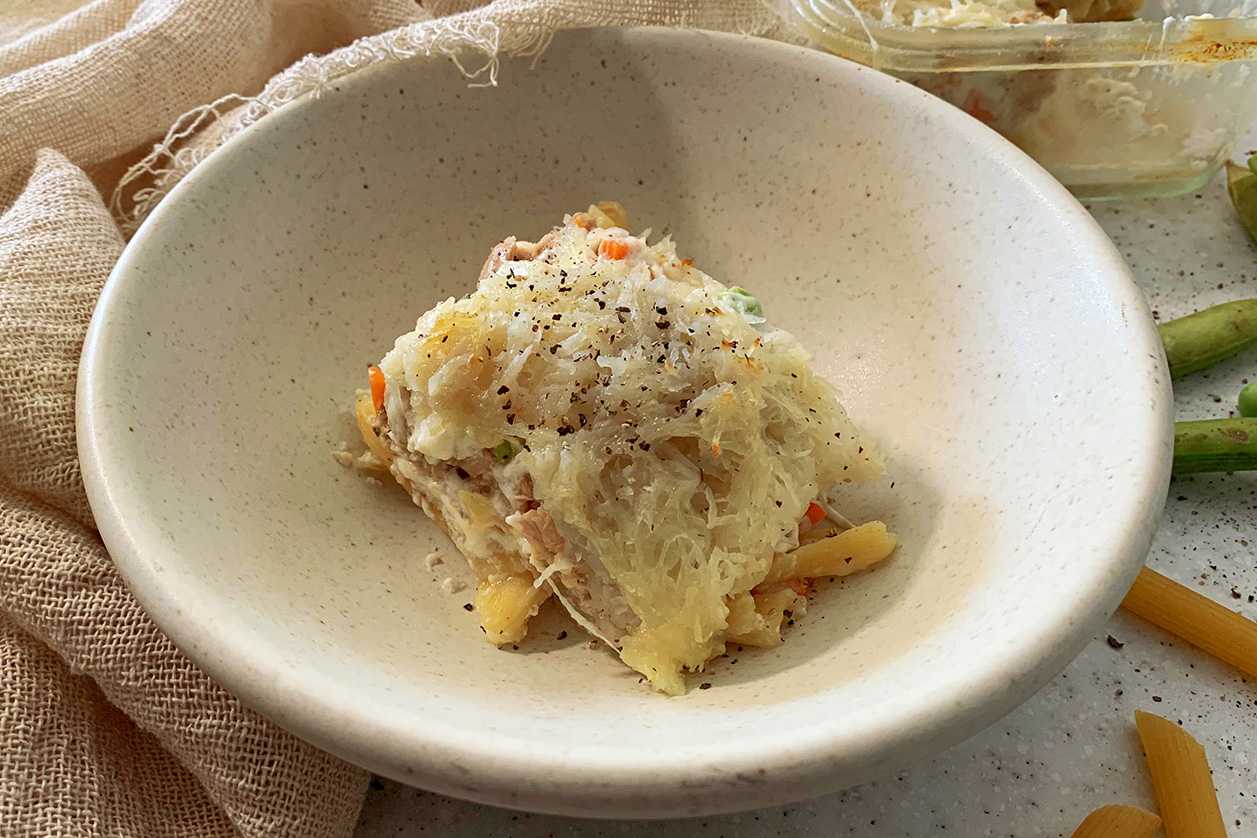 Penne pasta covered with tuna and vegetable mixture topped with shredded potatoes in white bowl