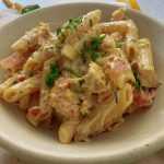 cooked penne pasta with chicken slices and bacon pieces in a cheesy sauce top with chopped parsley